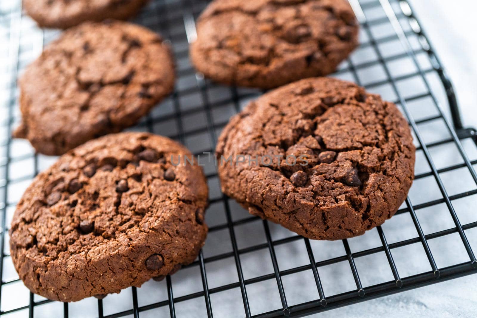 Freshly baked double chocolate chip cookies on a cooling rack.