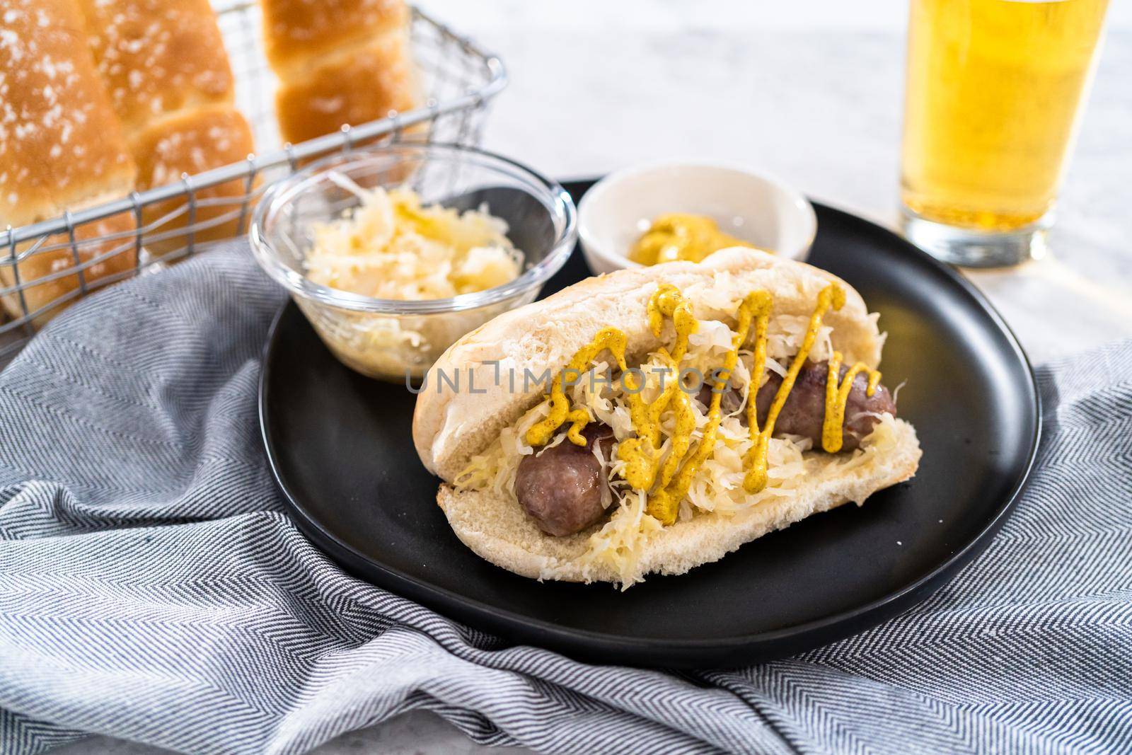 Beer brats with sauerkraut on large bun drizzled with mustard.