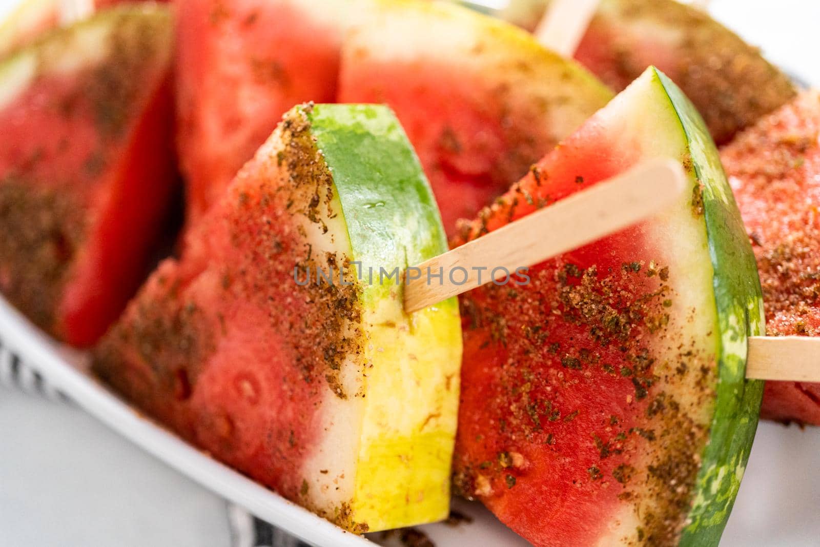 Chili lime watermelon pops on a white serving plate.