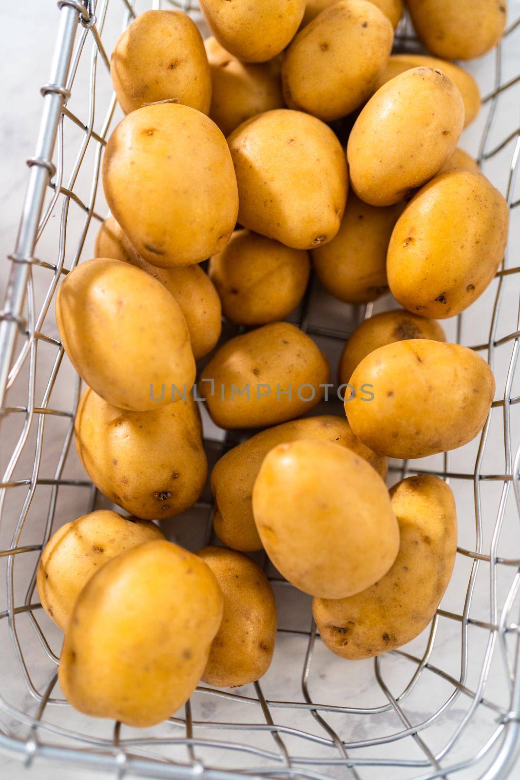 Pressure Cooker Baked Potatoes. Raw potatoes in a wire basket on the kitchen counter.