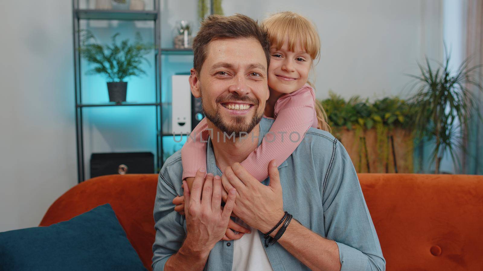 Pretty smiling cute child kid daughter embrace dad, look at camera. Happy beautiful family young adult single father foster nanny parent and toddler girl hug enjoy sweet tender love. Close-up portrait