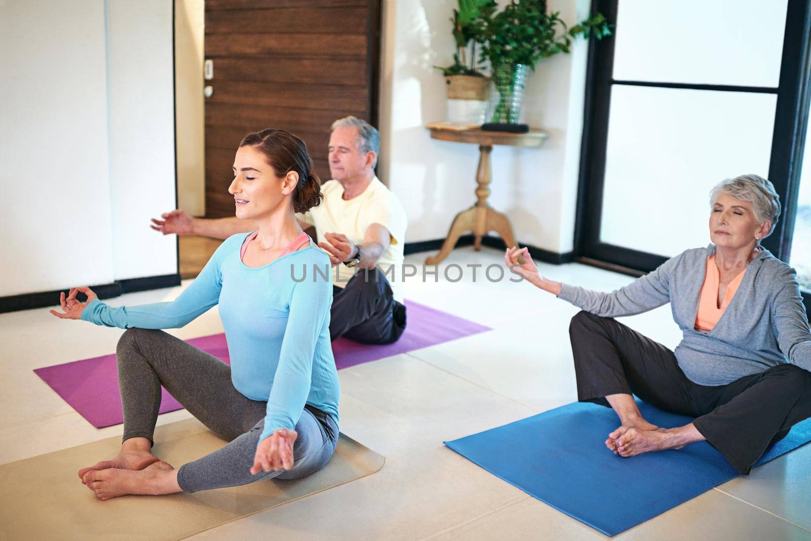 Finding zen. a yoga instructor guiding a senior couple in a yoga class