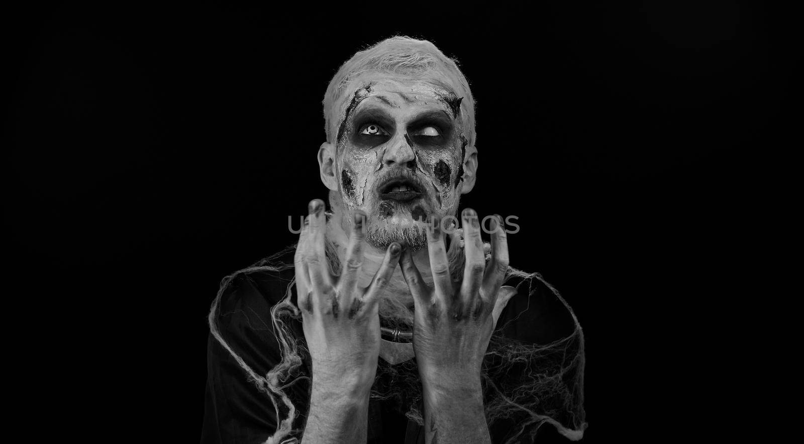 Dissatisfied frightening man with Halloween zombie bloody wounded makeup asking reason of failure, expressing disbelief irritation, feeling bored, disappointed in result, bad news. Sinister undead guy