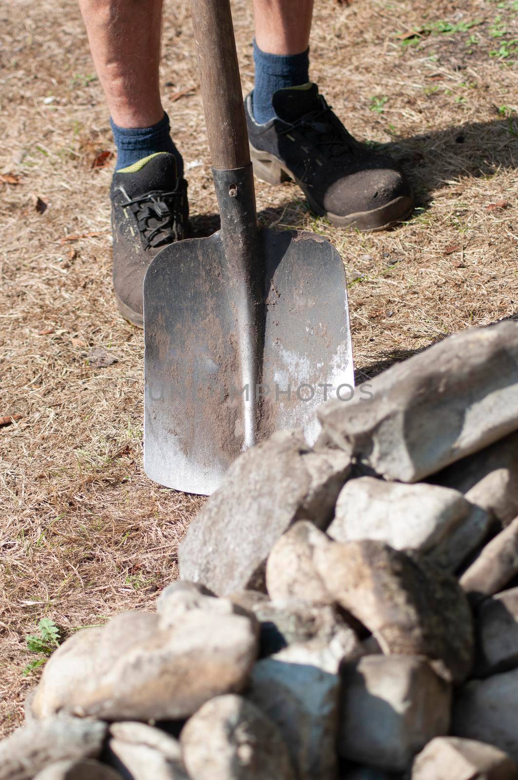 gardener in dirty work clothes and boots holds garden tools, shovel, seasonal spring work in the garden. High quality photo