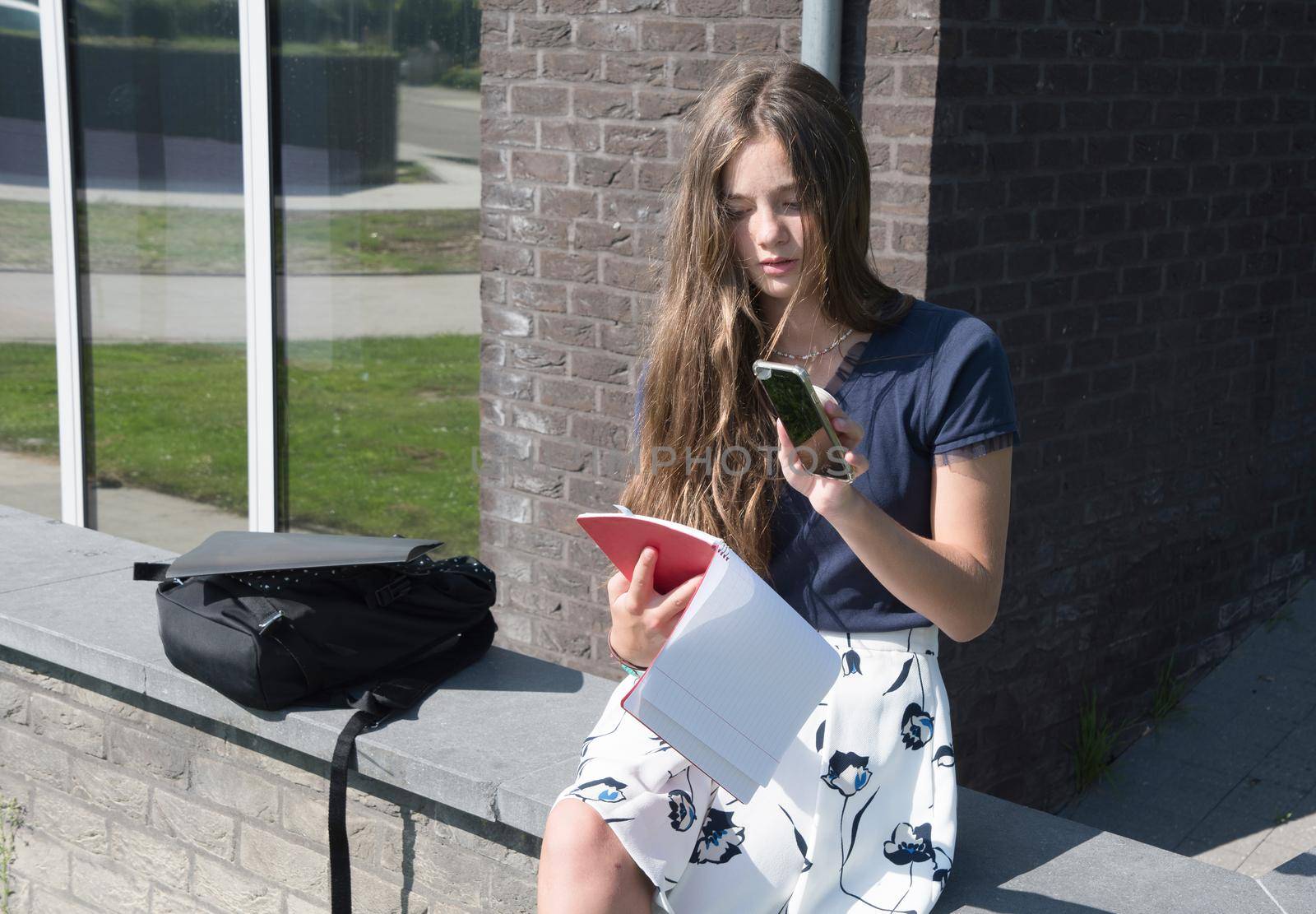 teenage girl student copying text using phone to send to her classmate by KaterinaDalemans