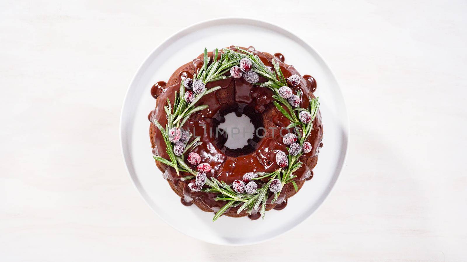 Step by step. Flat lay. Chocolate bundt cake with chocolate frosting decorated with fresh cranberries and rosemary covered in a white sugar.