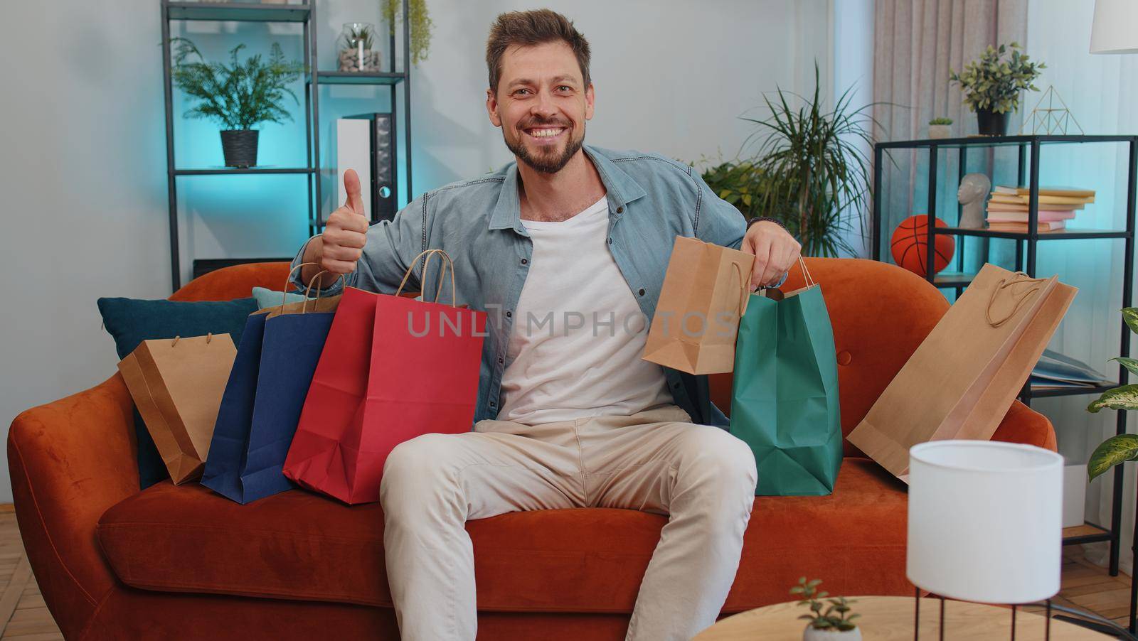 Happy adult man shopaholic consumer came back home after online shopping sale with bags at home by efuror