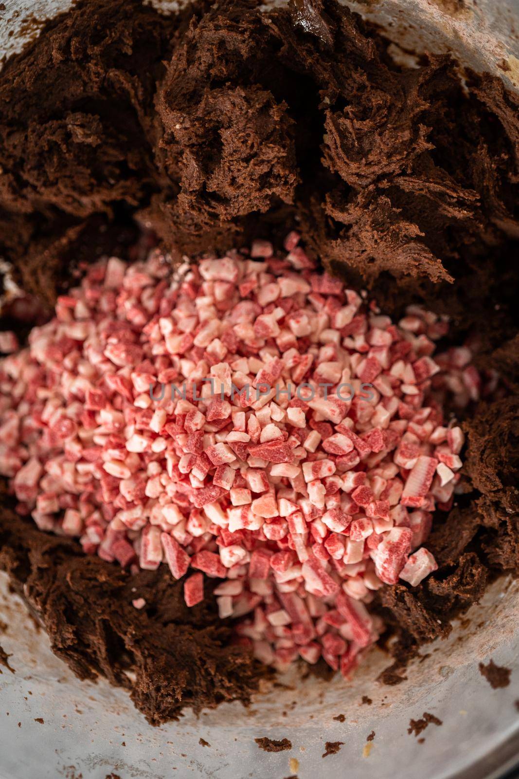 Folding in peppermint chocolate chips into a chocolate cookie dough to bake chocolate cookies with peppermint chips.