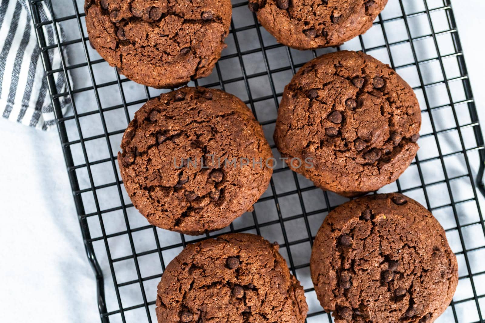 Freshly baked double chocolate chip cookies on a cooling rack.