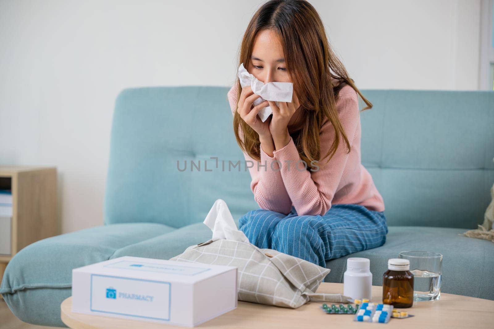 Sick woman. Asian young girl cold sick she sneeze with tissue paper on sofa, beautiful female health problem blowing nose use pharmacy kit box delivery service from hospital, delivery pharmacy concept