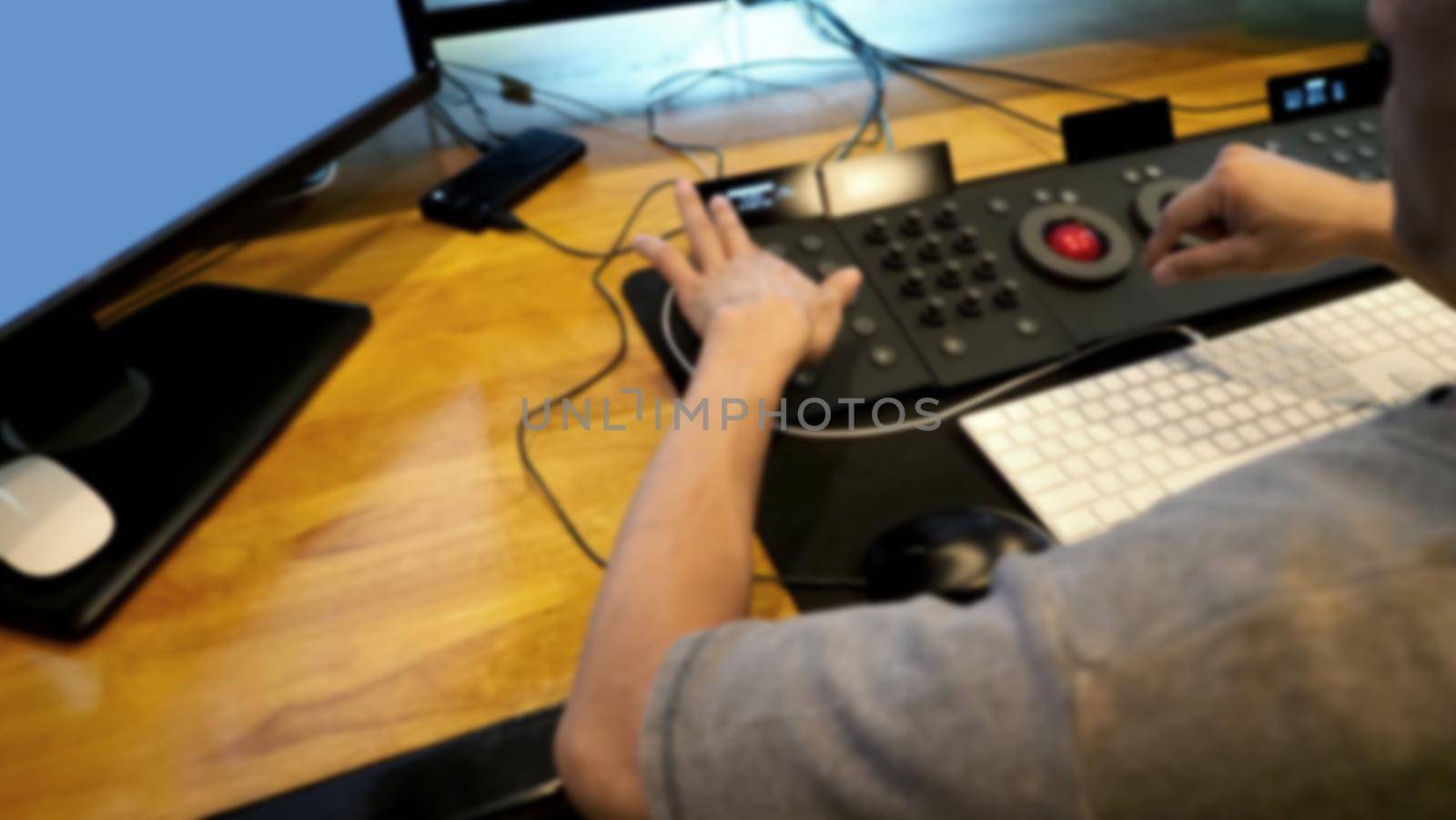 Blurry images of telecine controller machine and colorist man hand editing or adjusting color on digital video movie or film in the post production stage which very technical in the dark room lab.