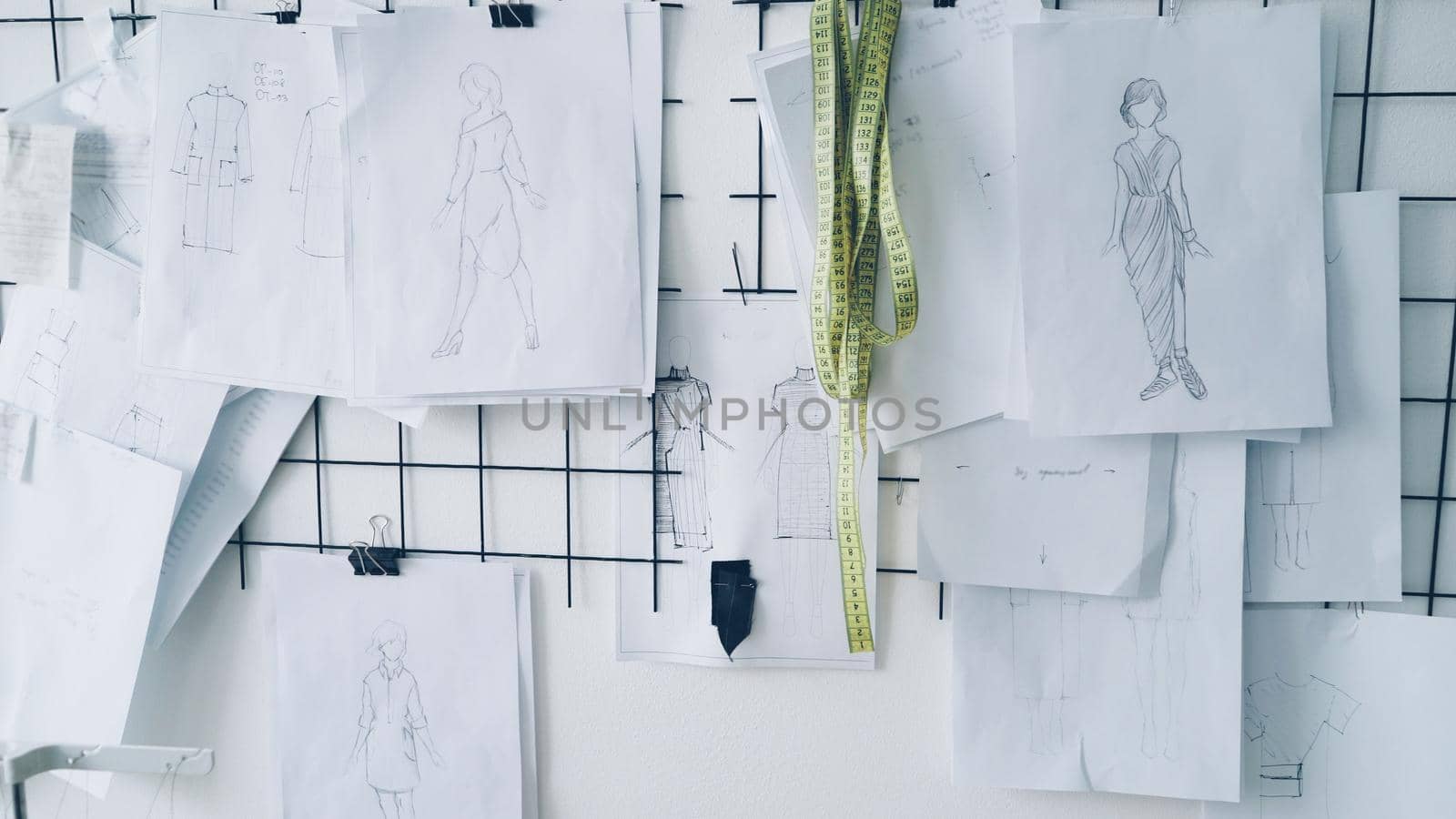 black and white sketches, drawings and notes with measurements of women's garments on wall in clothing design studio. Creating new collection concept. by silverkblack