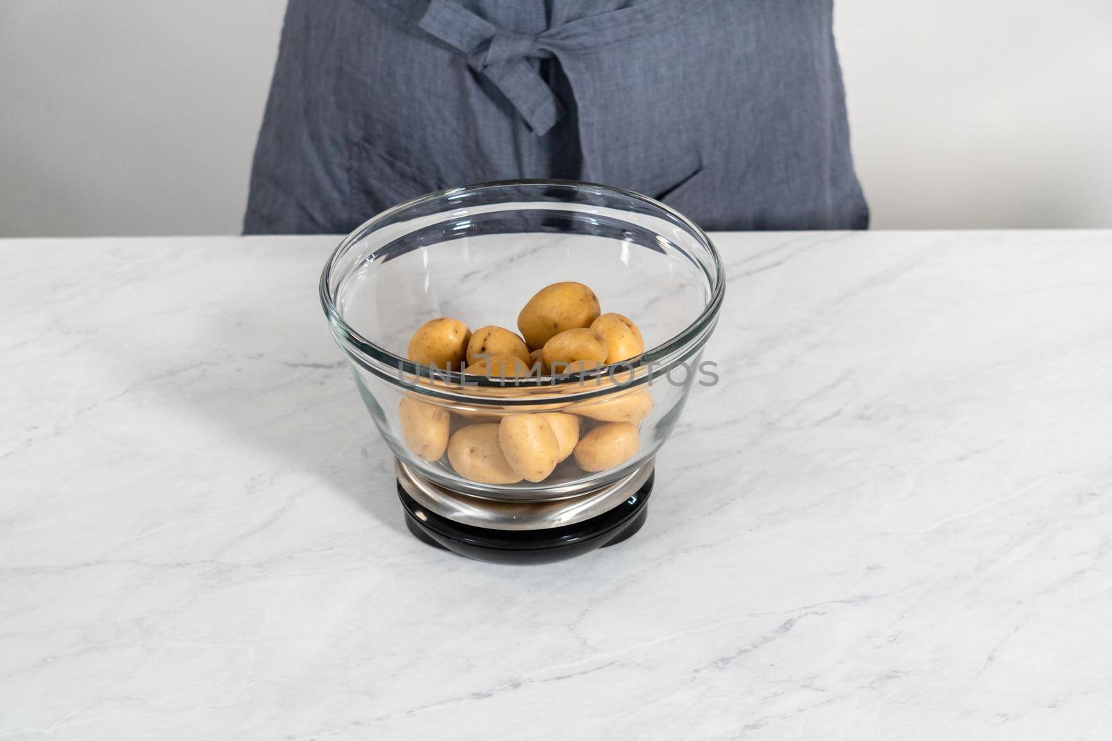 Pressure Cooker Baked Potatoes. Measuring raw potatoes in a glass mixing bowl on the kitchen scale.