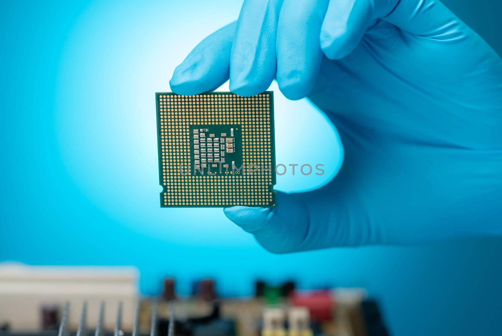 Electronic engineer hand holding computer chip on blue background. Chipset of electronic circuit board for PC motherboard. CPU chip. Electronic components. Computer hardware. Computer processor chip. by Fahroni