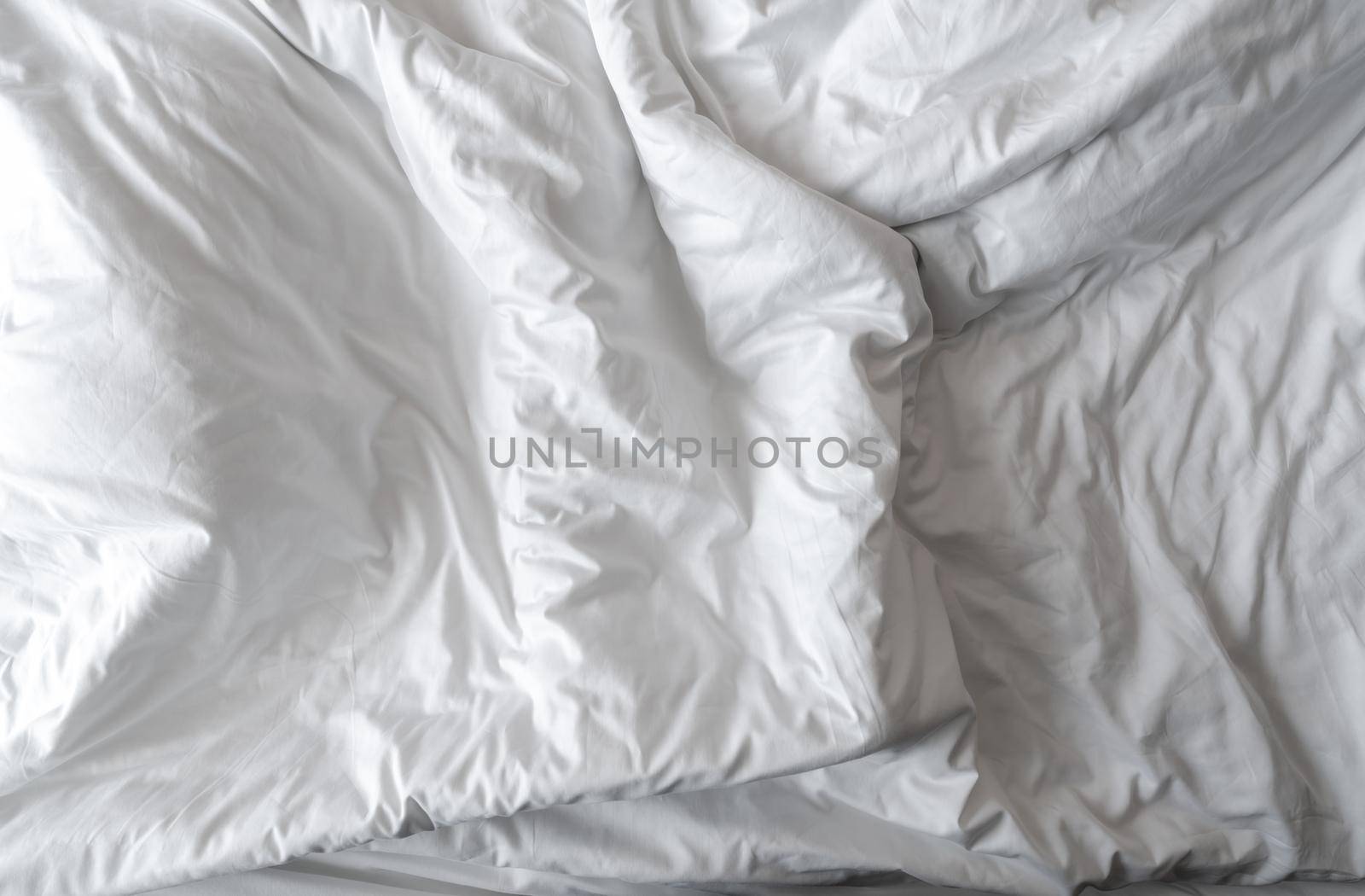 White linen blanket in hotel bedroom. Close-up detail of messy white blanket. Comfortable bed with soft white duvet. Sleep tight with good quality bedding household concept. Wrinkled white blanket. by Fahroni