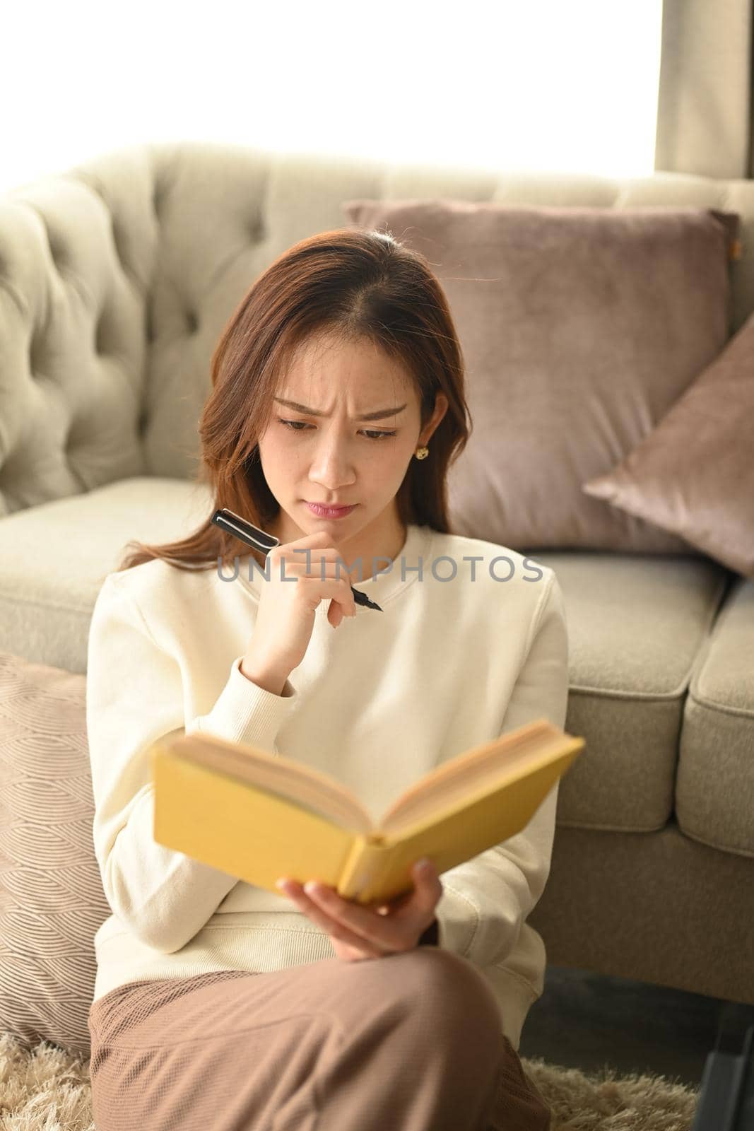 Serious young woman wearing warm sweater making important notes, agenda plan planning daily appointment on notebook.