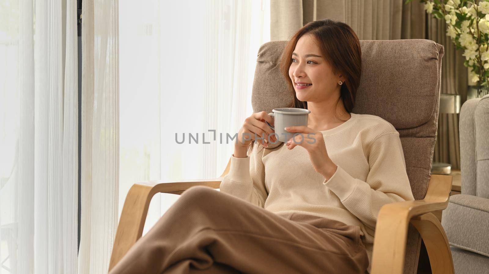 Calm woman in warm sweater drinking hot chocolate, enjoy stress free peaceful mood at home in sunny winter day by prathanchorruangsak