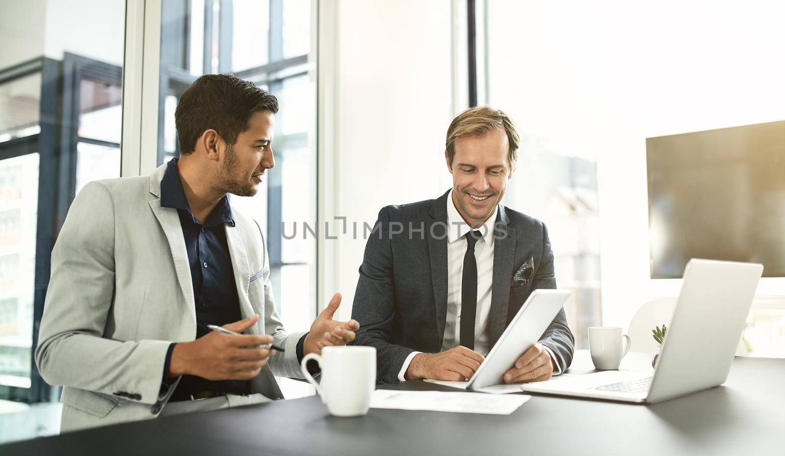 They are using technology to its true competitive advantage. two businesspeople having a discussion in an office. by YuriArcurs