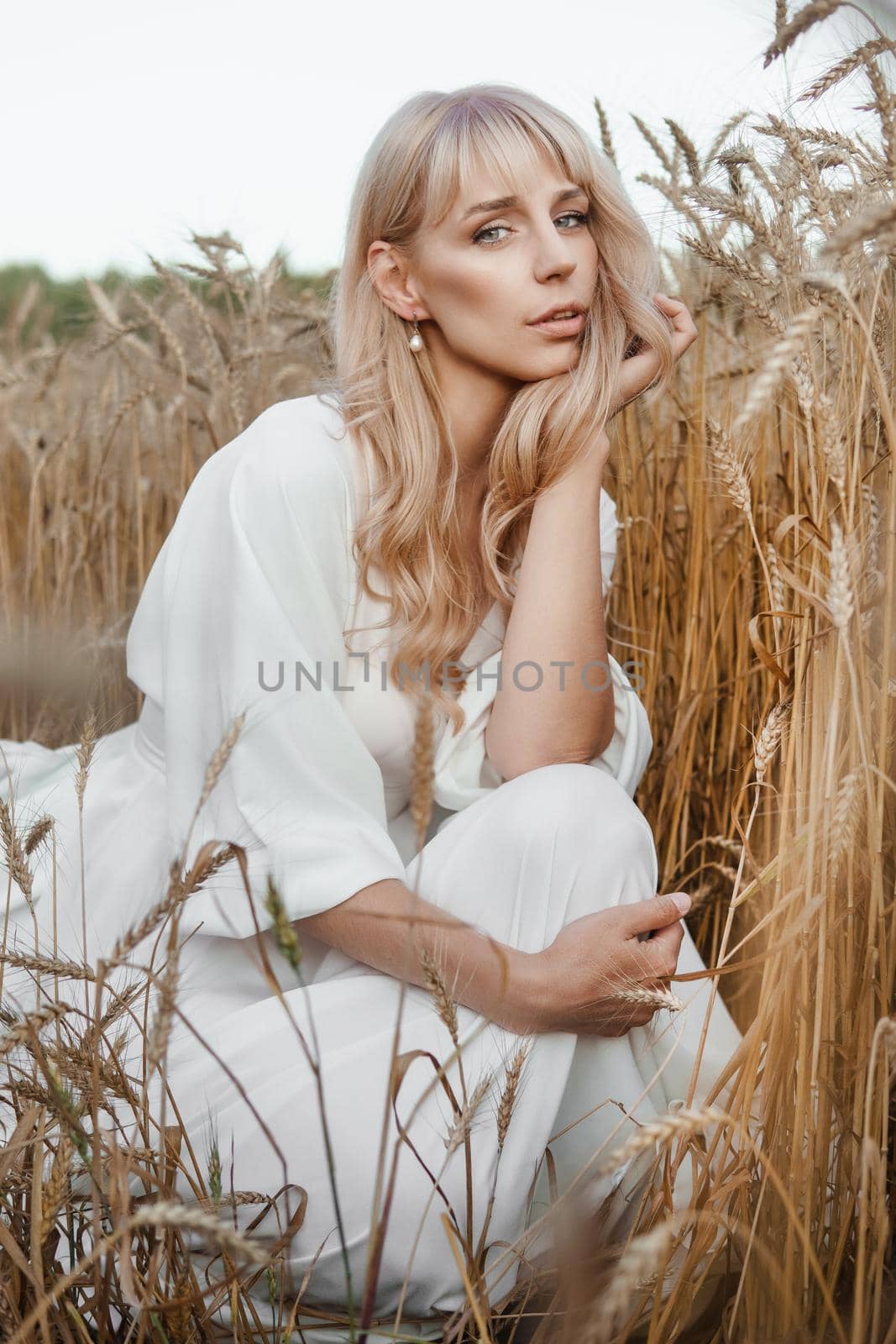 A blonde woman in a long white dress walks in a wheat field. The concept of a wedding and walking in nature by Annu1tochka