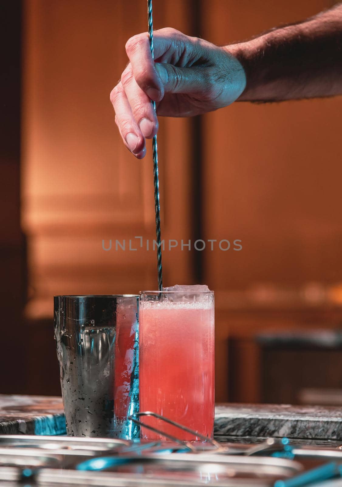 Bartender at nightclub preparing cocktails with bar equipment by Sonat