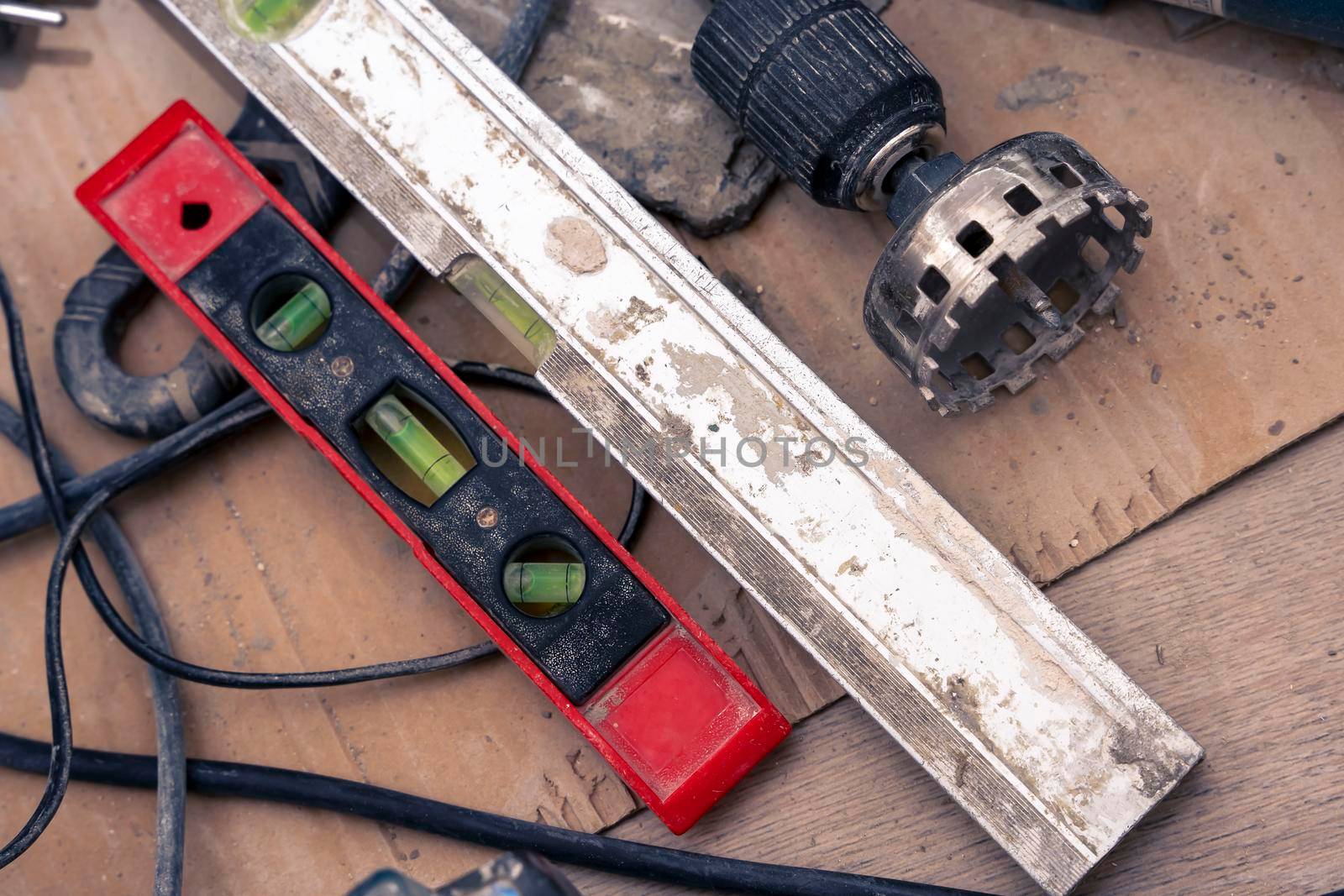 close-up of repair tools. diamond crown for drilling holes in ceramic tiles. close-up of a old bubble construction level lying on a ceramic tile floor during renovation