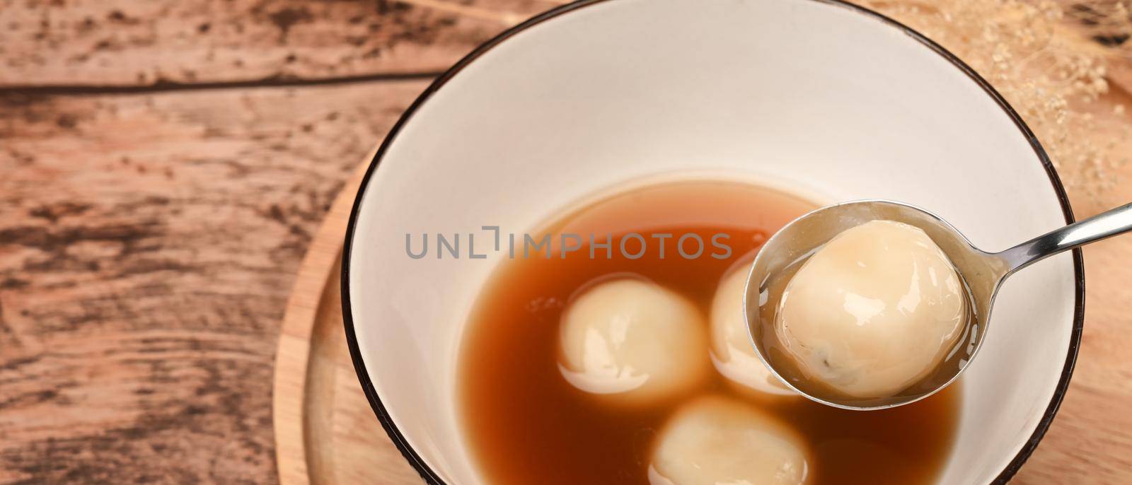 Black sesame dumplings in hot ginger soup on wooden table.