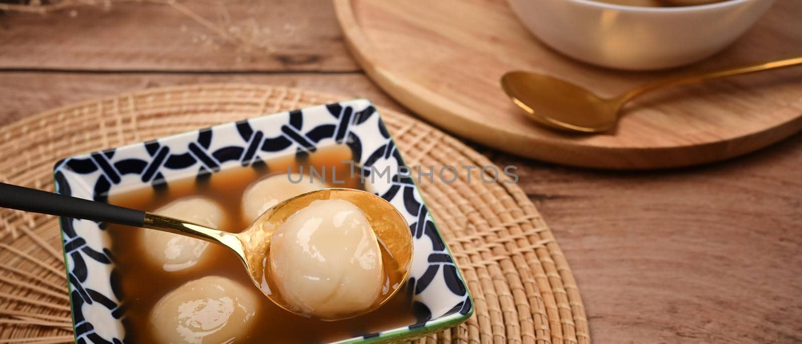 Rice dumpling balls with hot ginger soup in ceramic bowl.