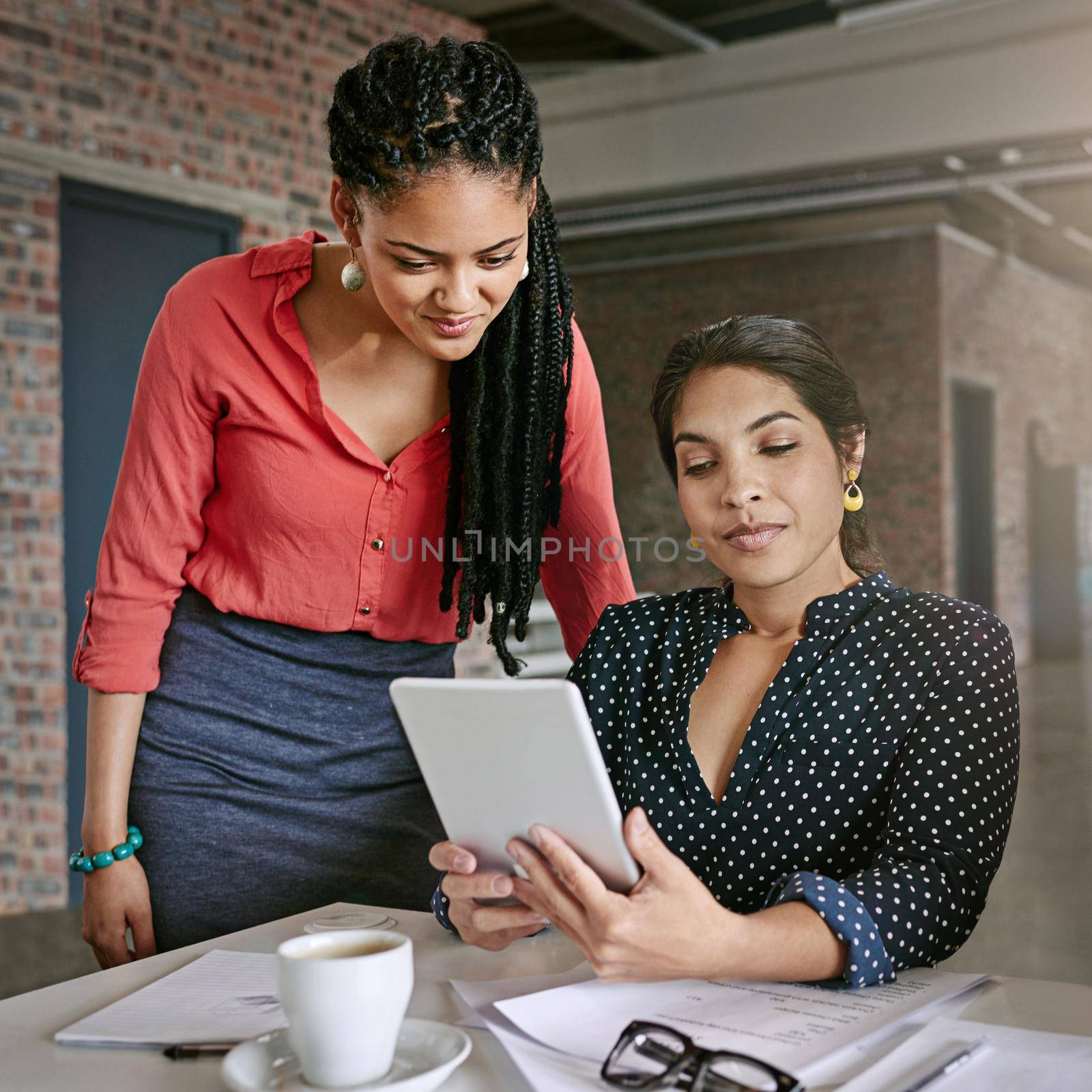 Lets take a further look into this. two colleagues using a digital tablet together in a modern office. by YuriArcurs