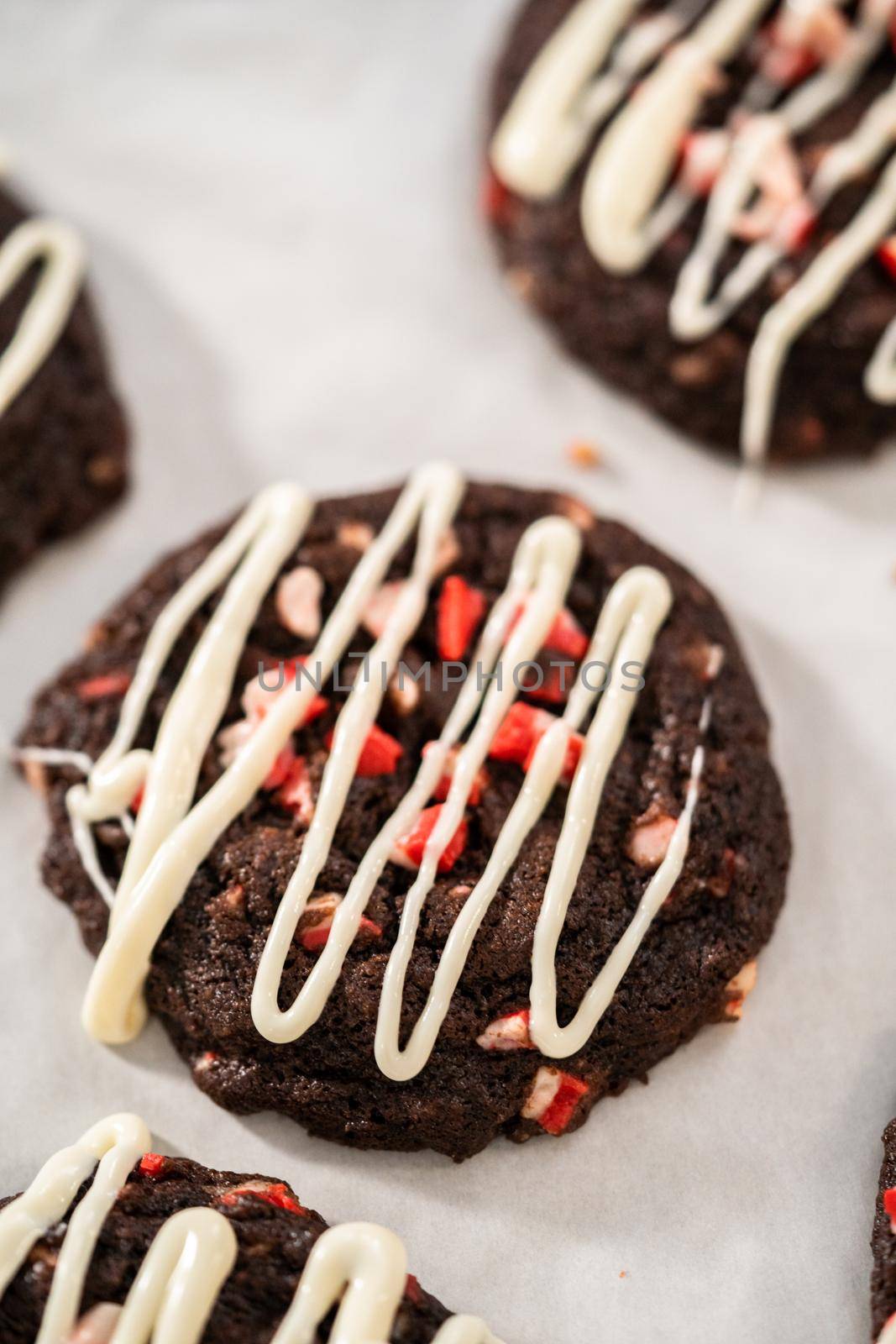 Freshly baked chocolate cookies with peppermint chips with a white chocolate drizzle on top.