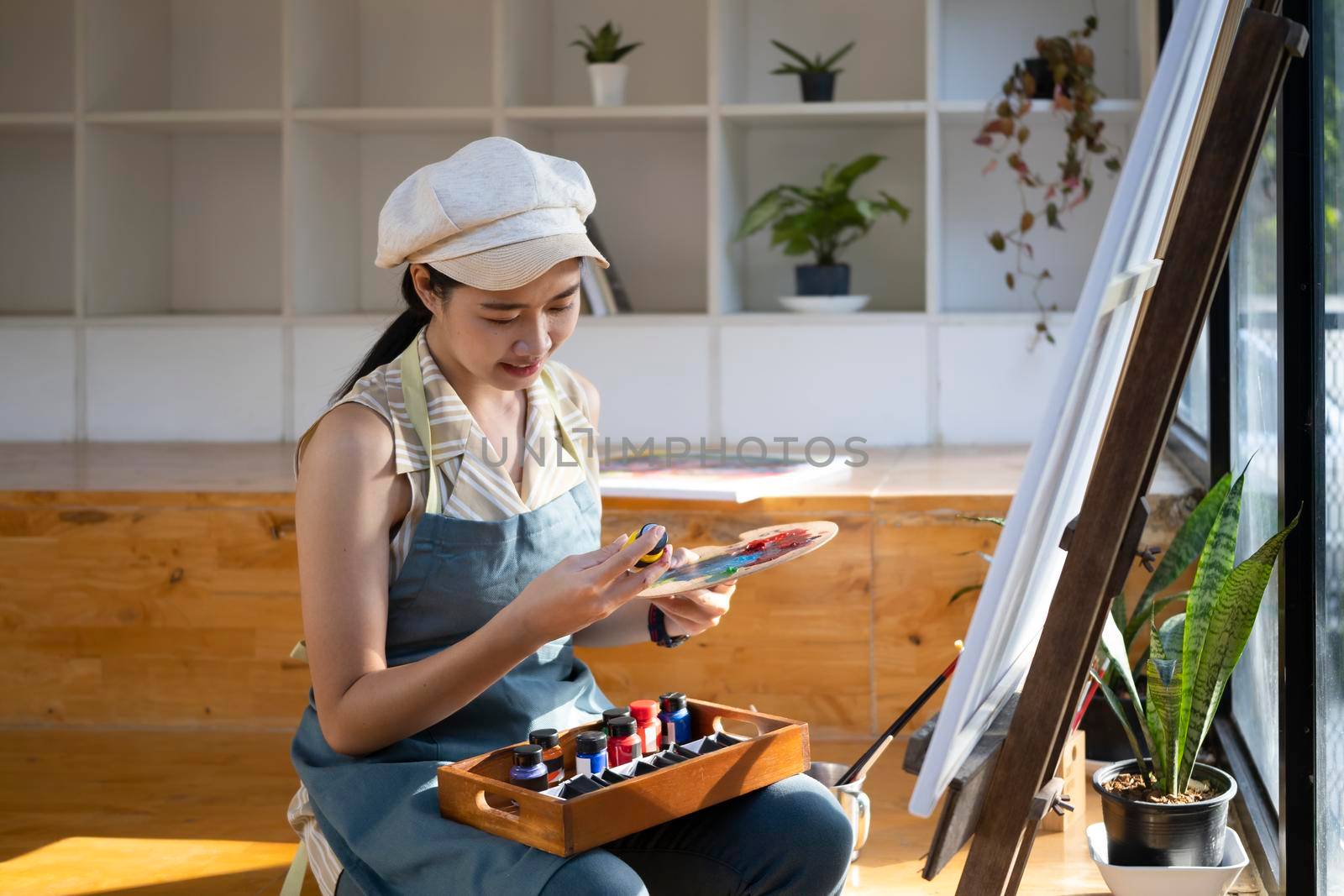 Positive asian woman painter painting in her studio.