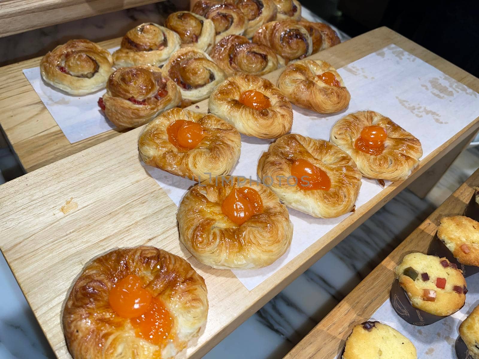 Lines of fresh baked sweet puff pastry stuffed with apricot and peach jelly, super delicious warm fresh buttery sweet puff pastry stuffed with apricot and peach, French and American baked pastries are enjoyed world wide on bakery shop, tasty multiple sweet puff pastry stuffed with apricot and peach