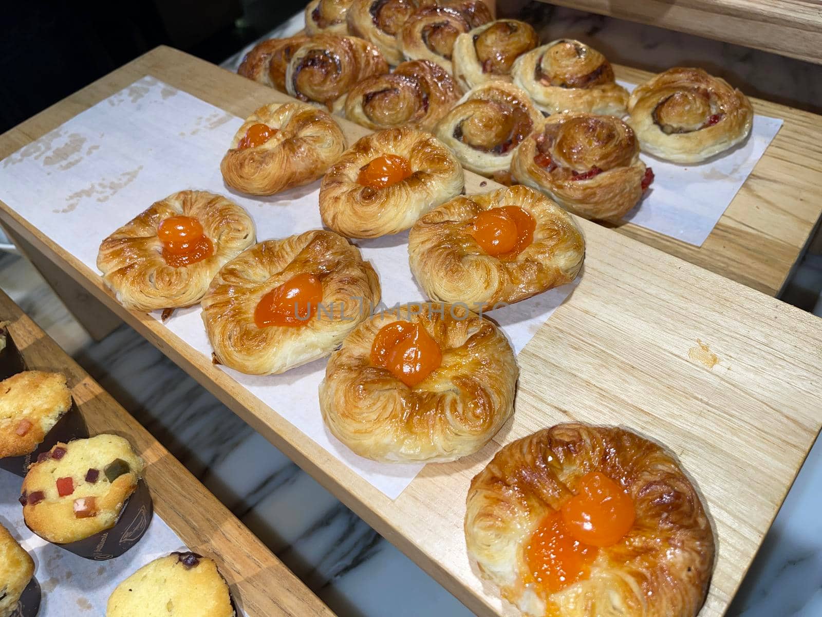 Lines of fresh baked sweet puff pastry stuffed with apricot and peach jelly, super delicious warm fresh buttery sweet puff pastry stuffed with apricot and peach, French and American baked pastries are enjoyed world wide on bakery shop, tasty multiple sweet puff pastry stuffed with apricot and peach