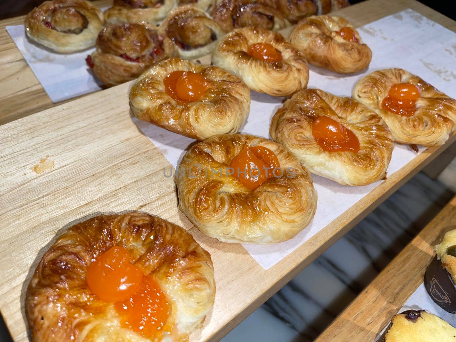 Lines of fresh baked sweet puff pastry stuffed with apricot and peach jelly, super delicious warm fresh buttery sweet puff pastry stuffed with apricot and peach, French and American baked pastries are enjoyed world wide on bakery shop, tasty multiple sweet puff pastry stuffed with apricot and peach
