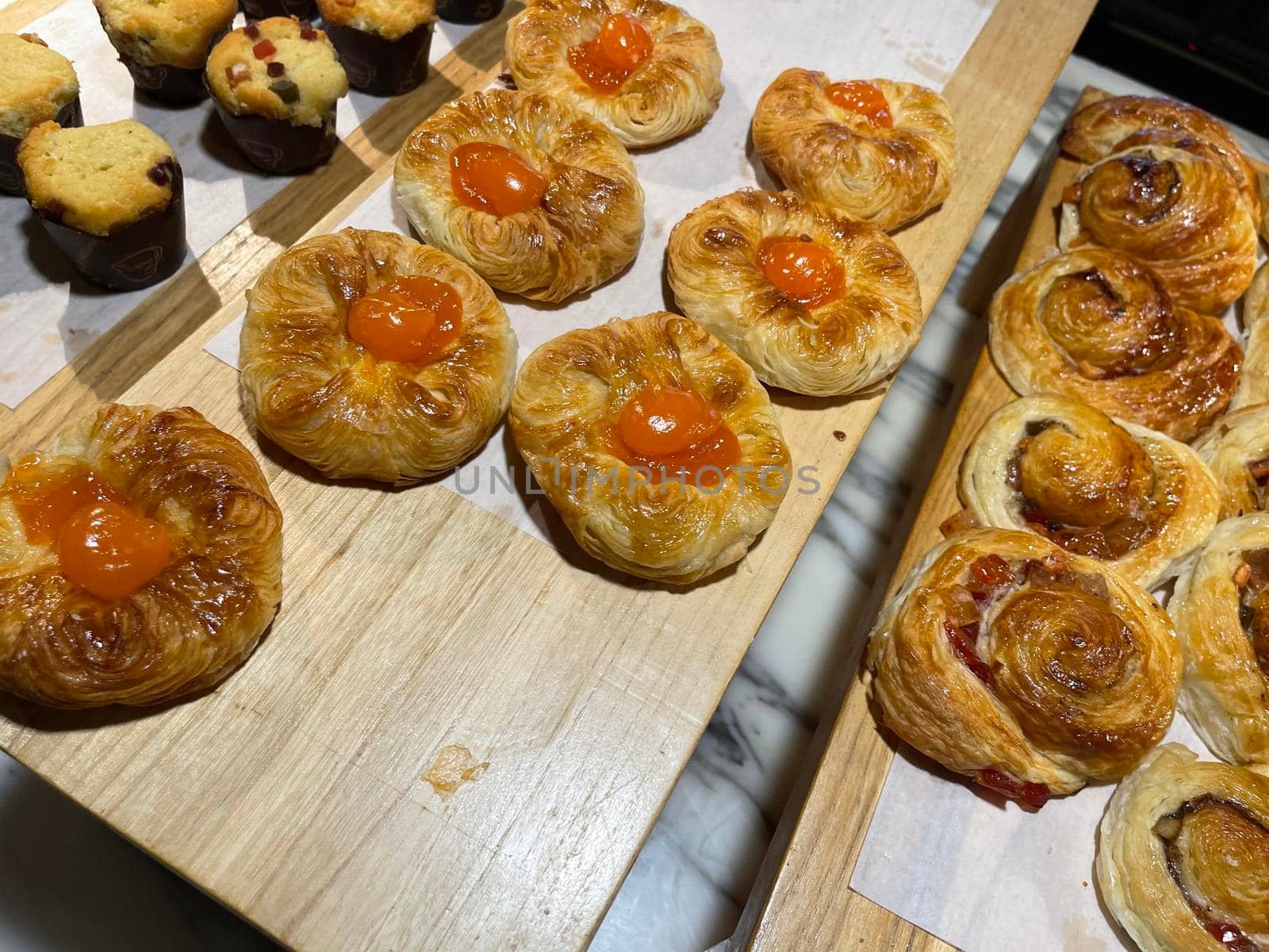 Lines of fresh baked sweet puff pastry stuffed with apricot and peach jelly, super delicious warm fresh buttery sweet puff pastry stuffed with apricot and peach, French and American baked pastries are enjoyed world wide on bakery shop, tasty multiple sweet puff pastry stuffed with apricot and peach