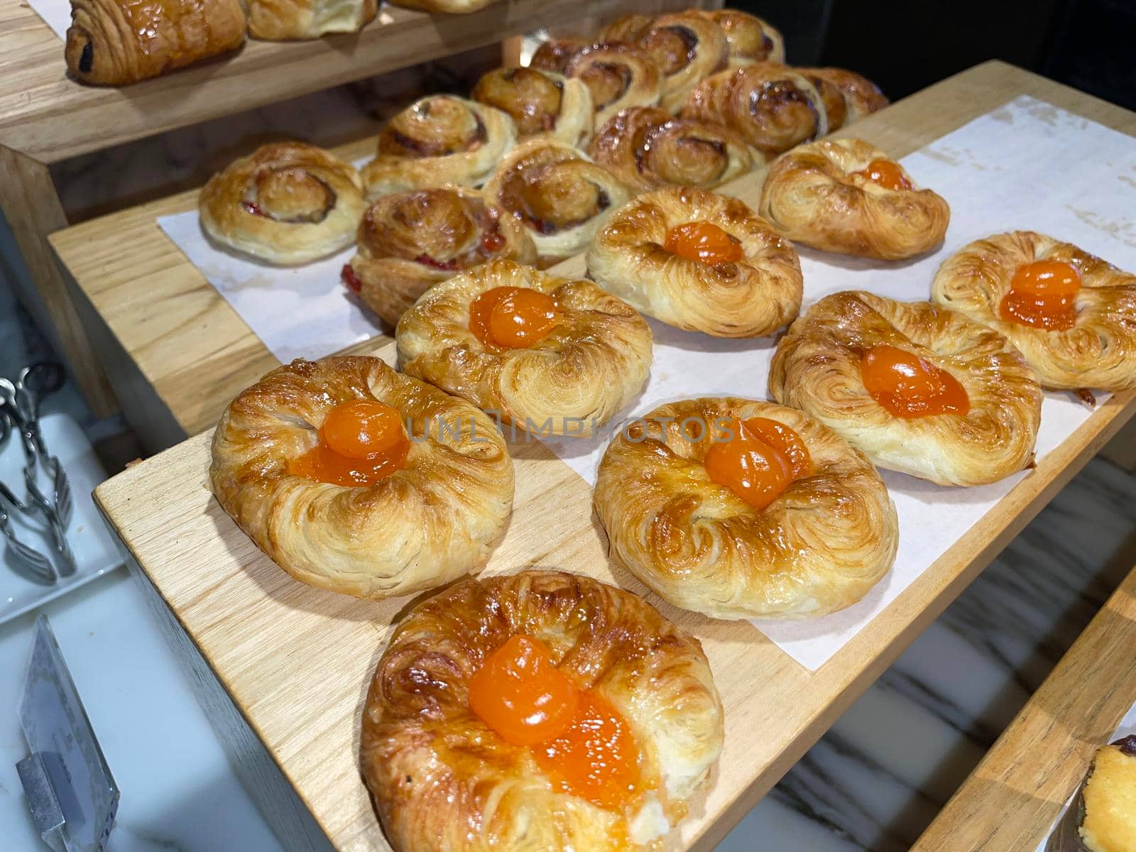 Lines of fresh baked sweet puff pastry stuffed with apricot and peach jelly, super delicious warm fresh buttery sweet puff pastry stuffed with apricot and peach, French and American baked pastries are enjoyed world wide on bakery shop, tasty multiple sweet puff pastry stuffed with apricot and peach