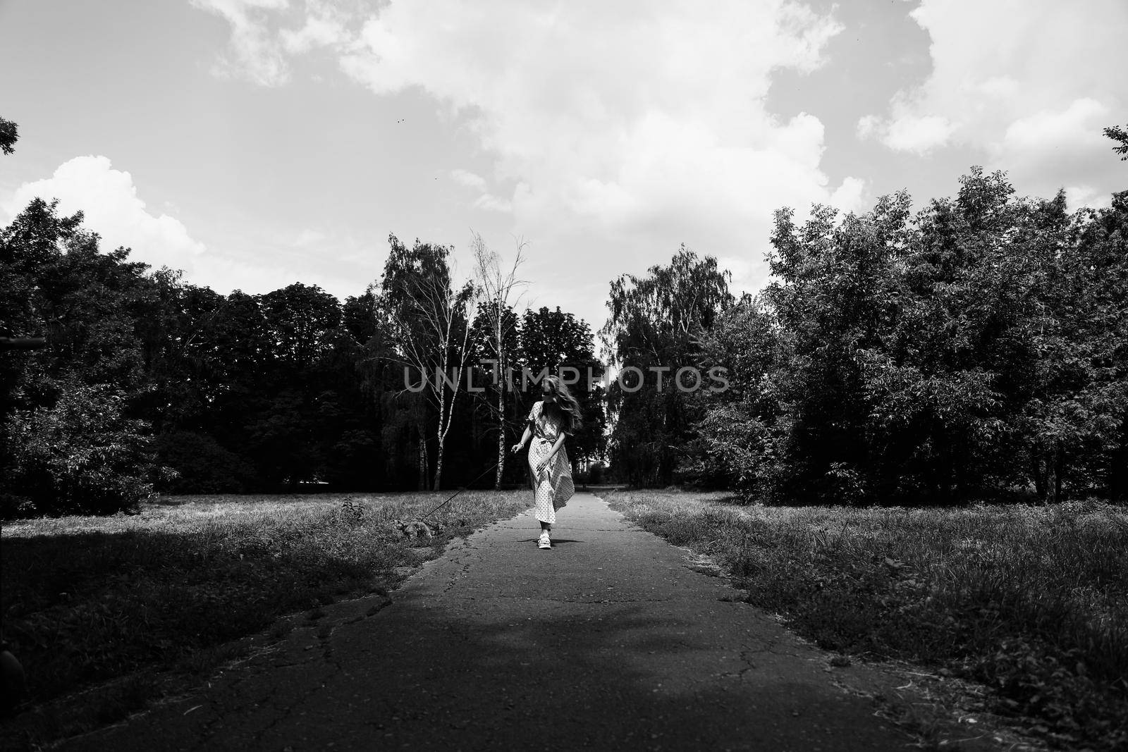 A young woman in a protective medical face mask walks with a Scottish Straight kitten in the park during the covidvirus covid-19 pandemic.