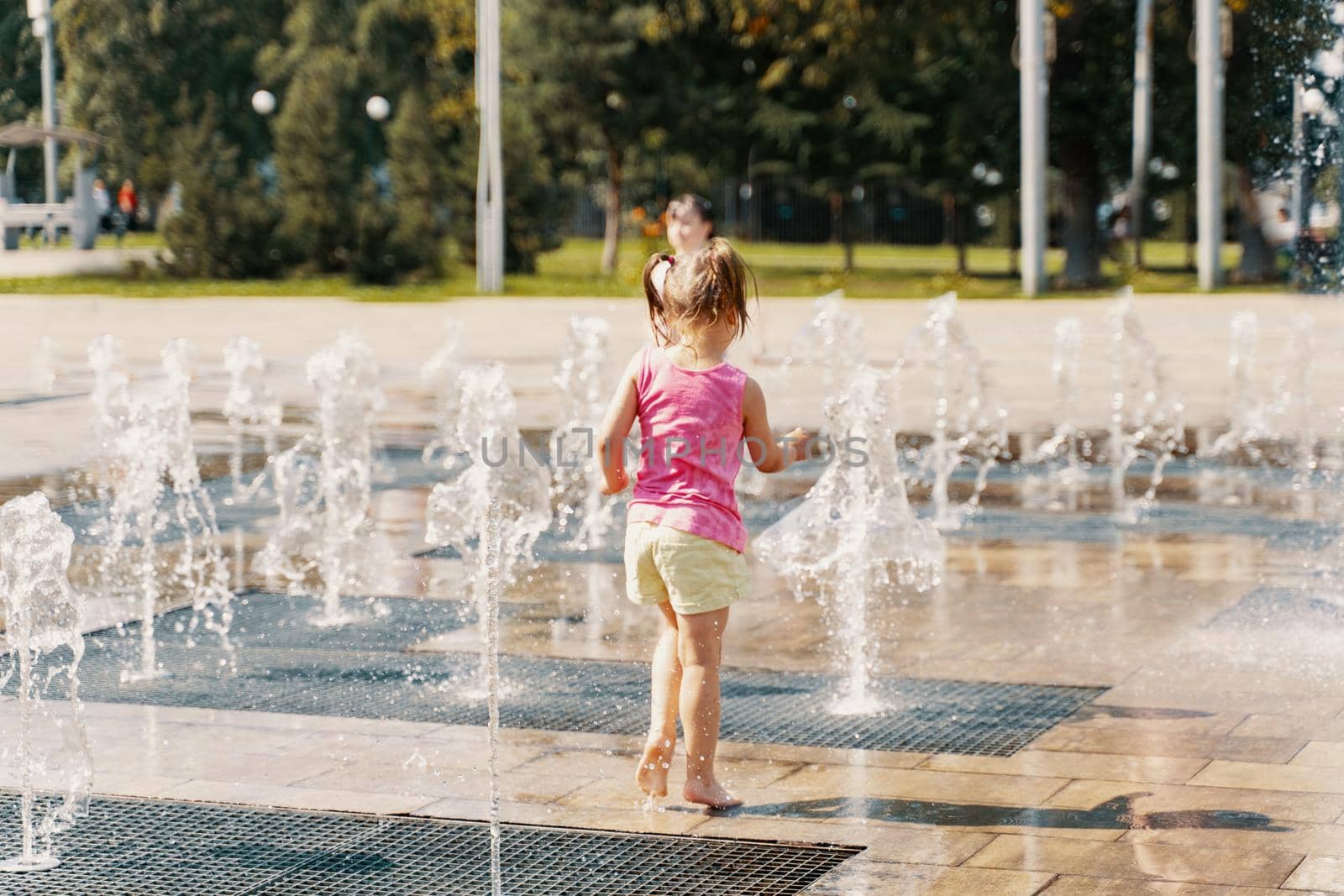 child girl playing in the water jets of the fountain by Lena_Ogurtsova