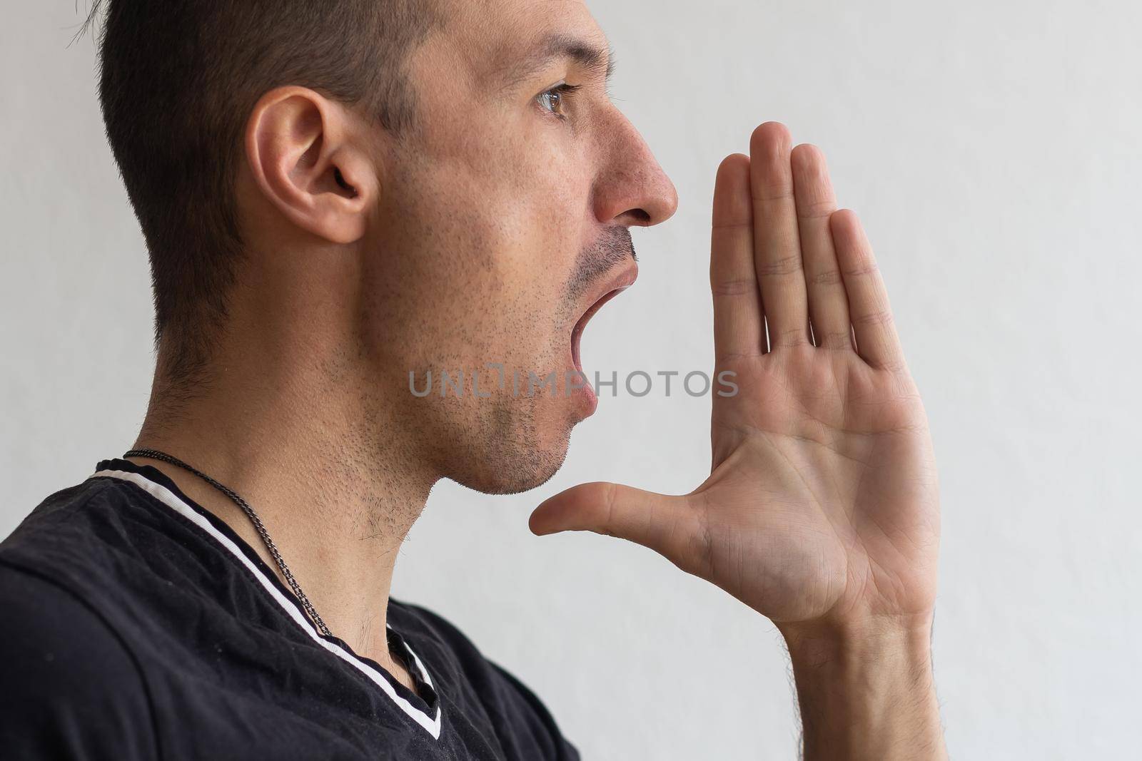 Handsome happy man wearing T-shirt, guy speaking loudly, isolated on white background by Andelov13