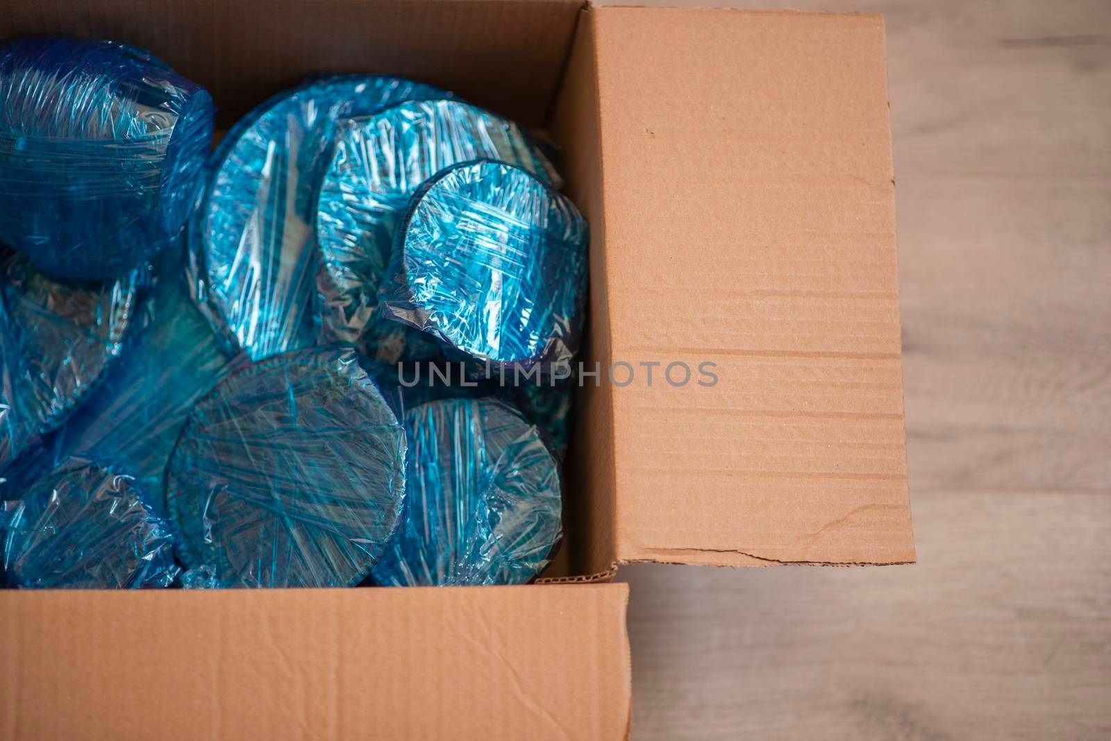 Glassware wrapped with blue wrapping nylon at the bottom of a cardboard box. High quality photo