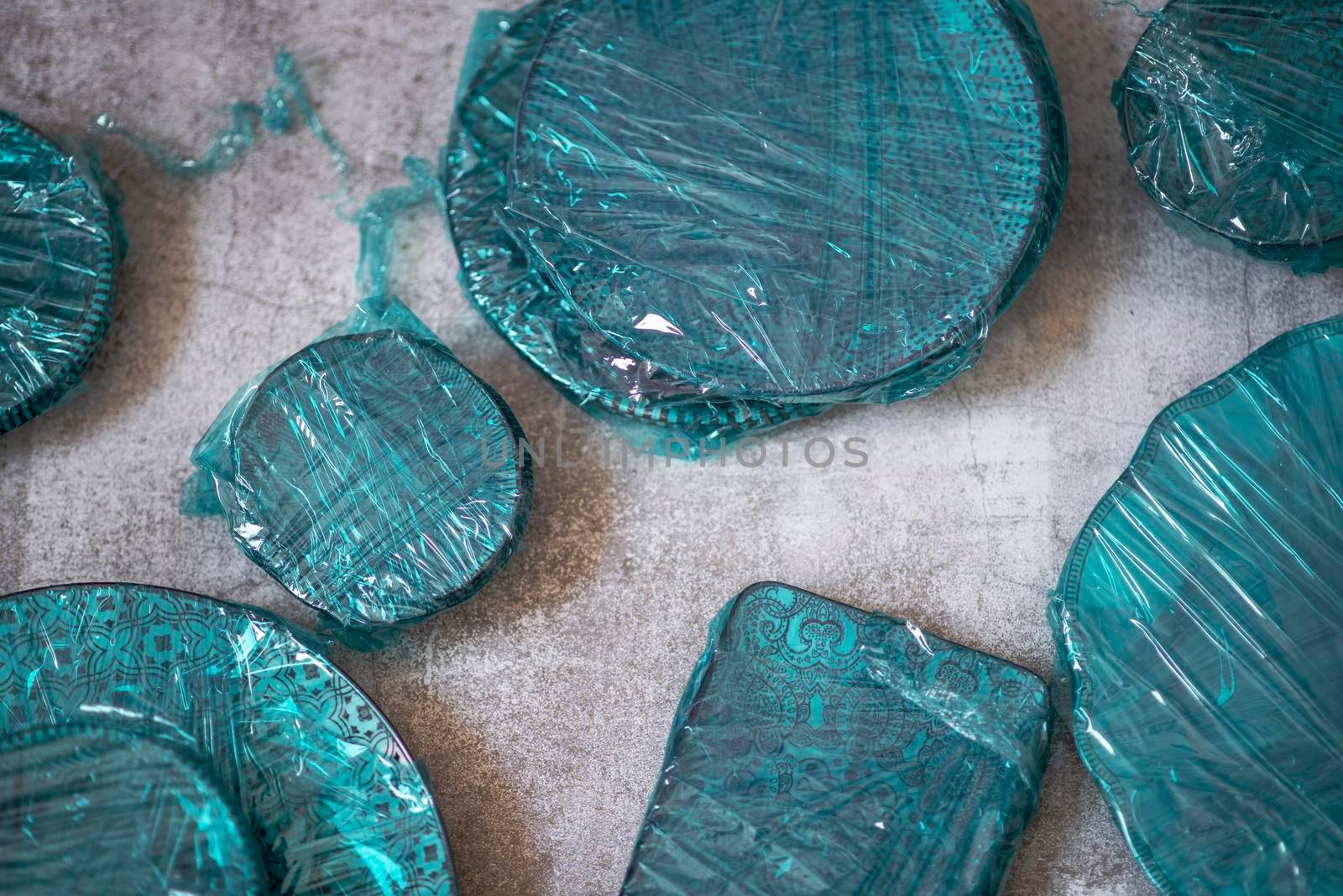 Small plates wrapped in blue cling film placed on brown wooden floor background. Top view. Copy Space by avirozen
