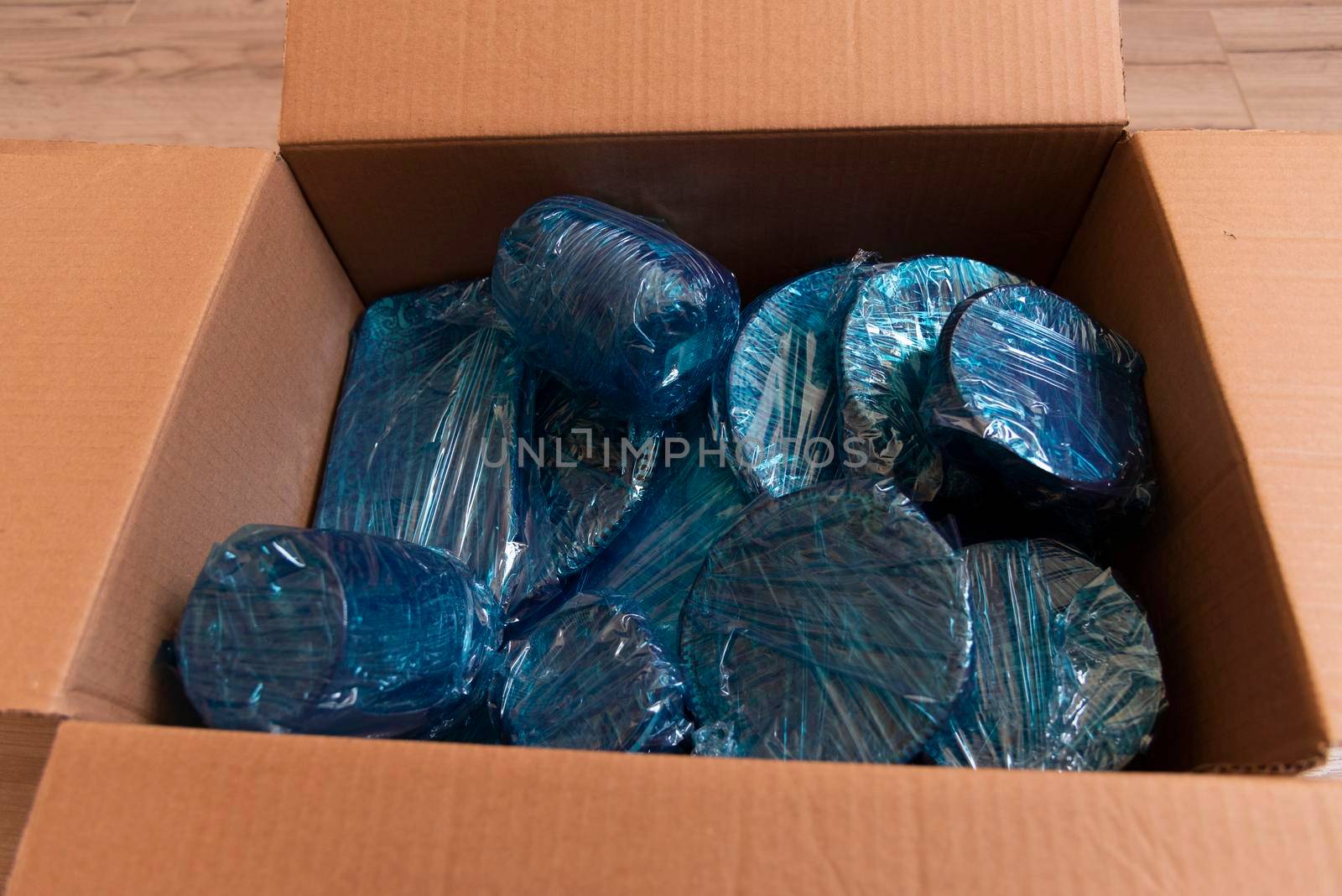 Glassware wrapped with blue wrapping nylon at the bottom of a cardboard box. Glassware wrapped in a box by avirozen