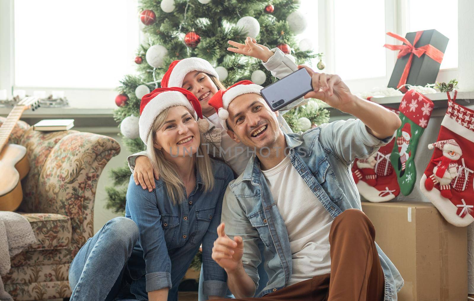 family having fun and playing together near Christmas tree indoors