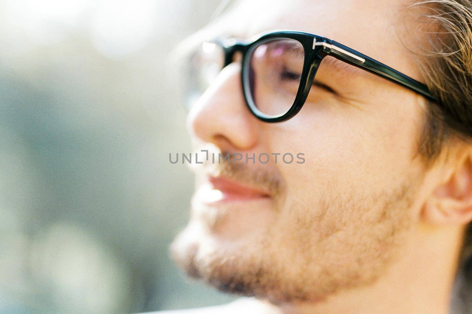 Young man with glasses squints at the sun. Profile. Portrait. High quality photo