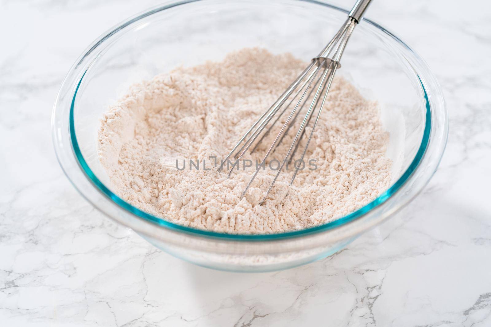 Mixing dry ingredients in a large glass mixing bowl to bake eggnog cookies with a chocolate gingerbread man.