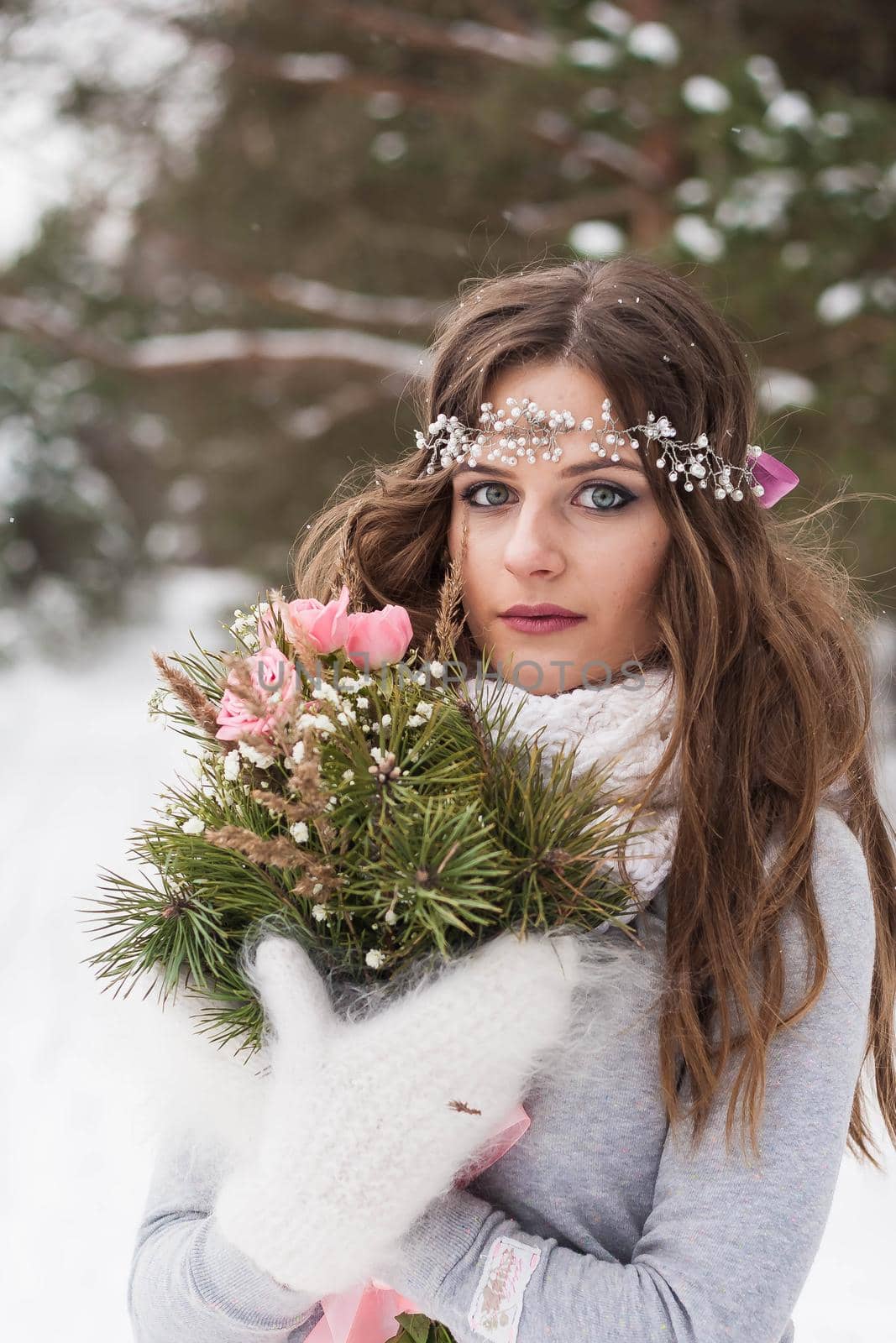 Beautiful bride in a white dress with a bouquet in a snow-covered winter forest. Portrait of the bride in nature.