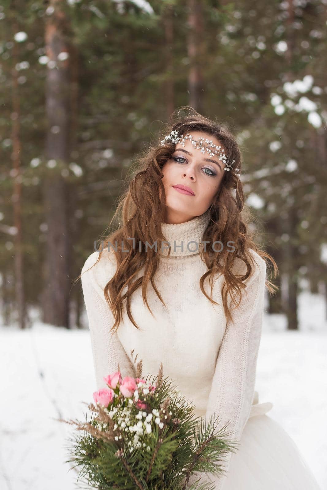 Beautiful bride in a white dress with a bouquet in a snow-covered winter forest. Portrait of the bride in nature.Beautiful bride in a white dress with a bouquet in a snow-covered winter forest. Portrait of the bride in nature.