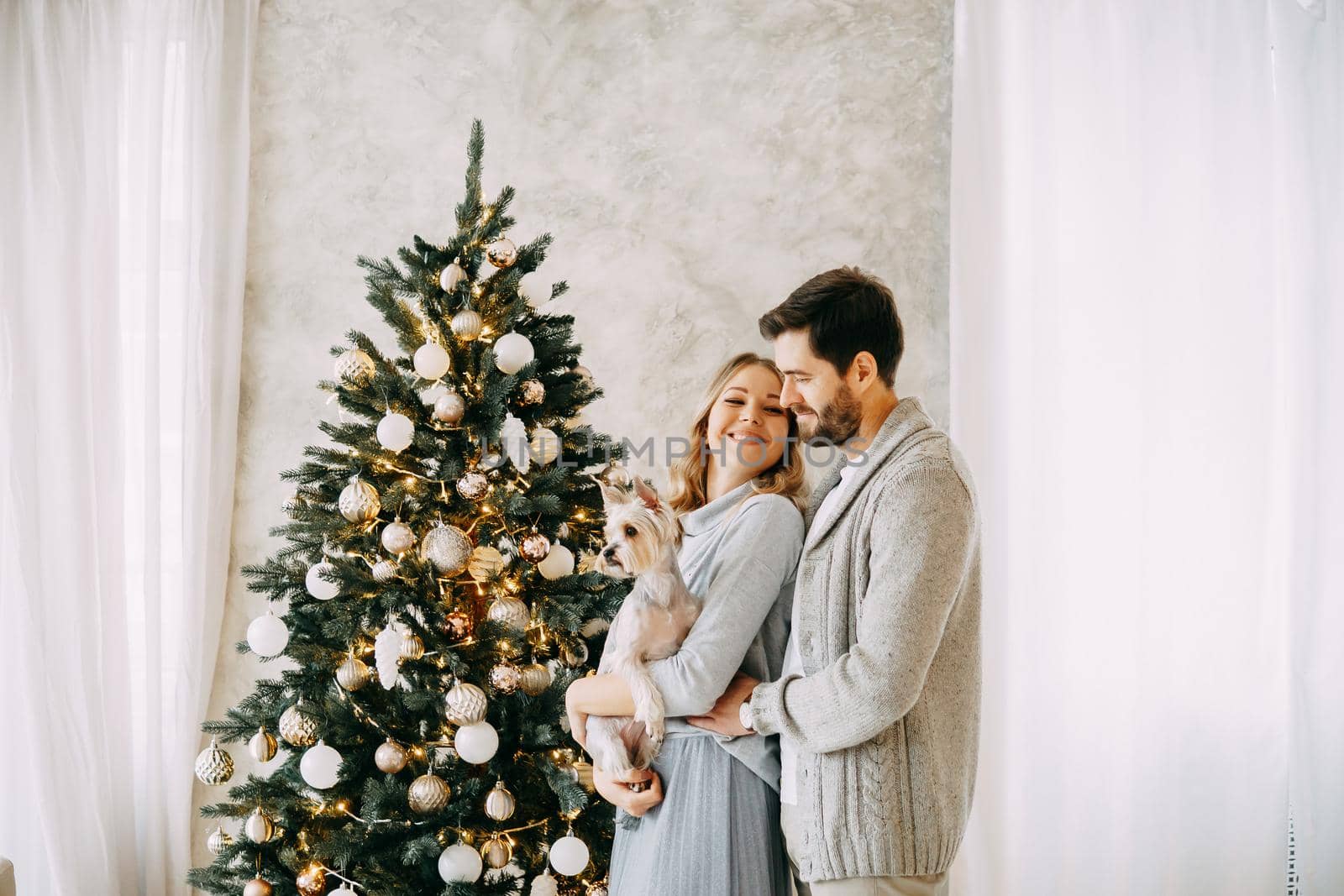 Happy family: mom, dad and pet. Family in a bright New Year's interior with a Christmas tree.