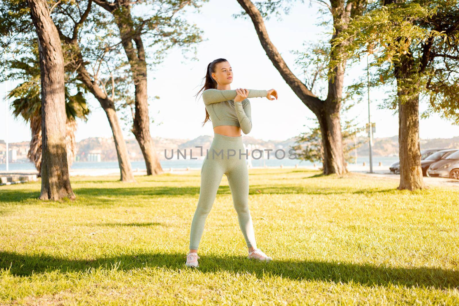 Woman Stretching And Warming-Up Before Running. Fit sport woman stretching her body warm up before workout outdoor. The girl in sportswear exercises outside in summer park for health and wellbeing.