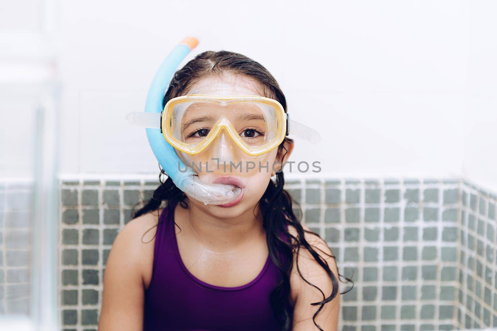 portrait of a happy pretty little girl with snorkel goggles in the tub while taking a bath in the bathtub, kids hygiene concept, copy space for text