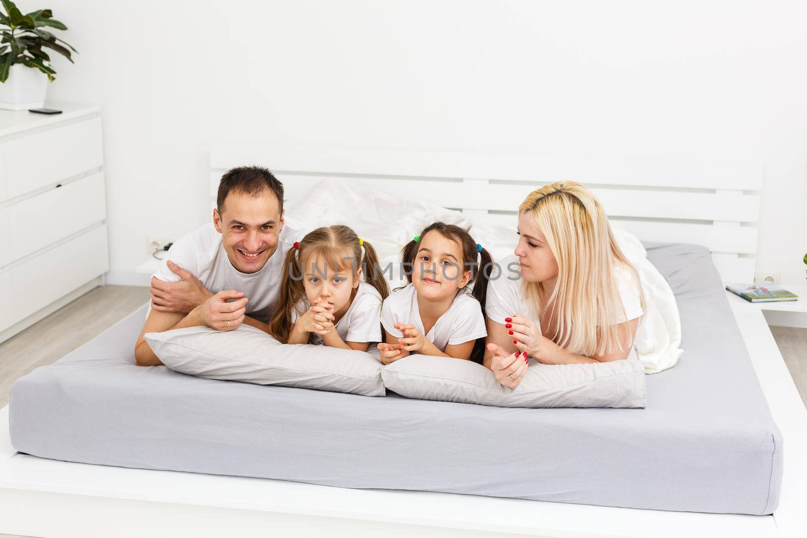 Young family resting together in parent's bed.